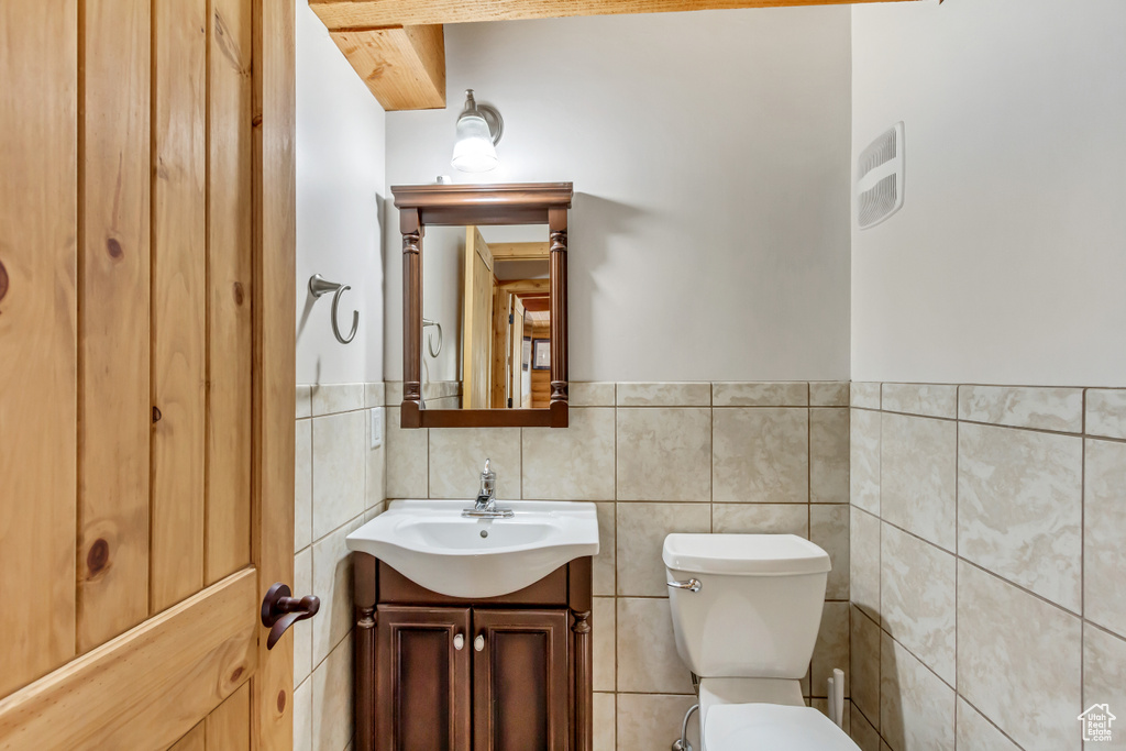 Bathroom with vanity, decorative backsplash, toilet, and tile walls