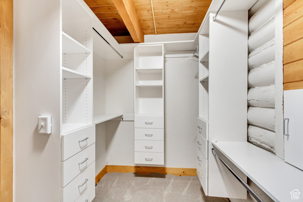 Spacious closet featuring beamed ceiling and light carpet