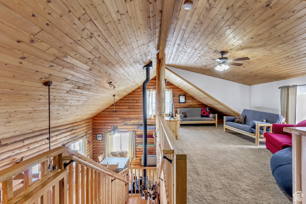 Interior space featuring wooden ceiling, vaulted ceiling, carpet, and rustic walls