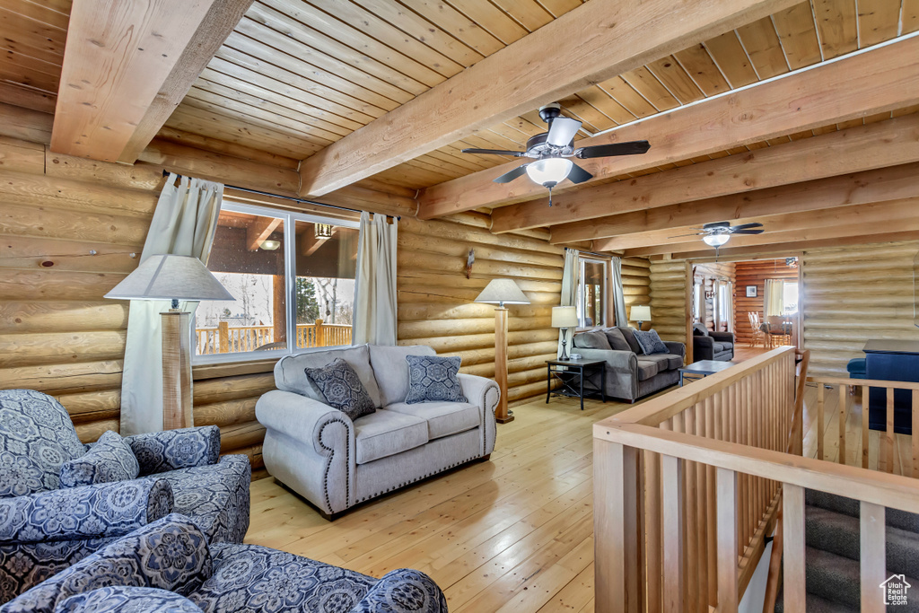 Living room featuring rustic walls, wood ceiling, ceiling fan, beamed ceiling, and light hardwood / wood-style floors