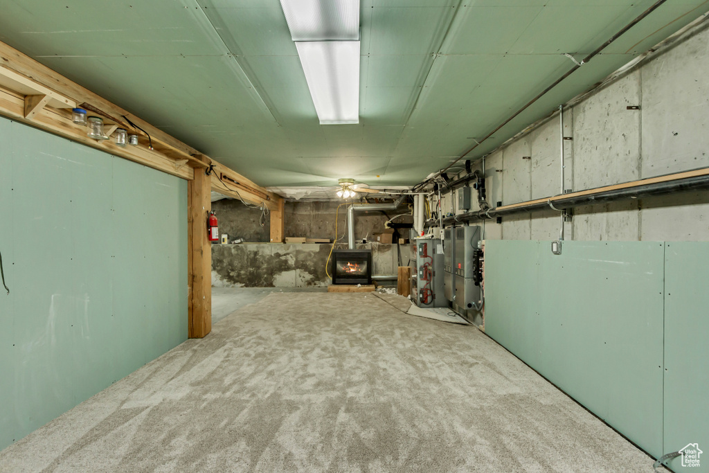 Basement featuring carpet flooring, a wood stove, and water heater