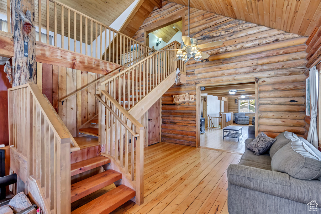 Interior space featuring high vaulted ceiling, wood ceiling, light wood-type flooring, and rustic walls