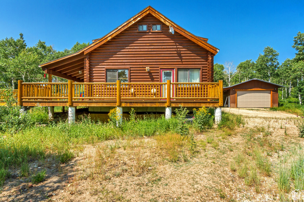 View of front of home with a garage, a wooden deck, and an outdoor structure