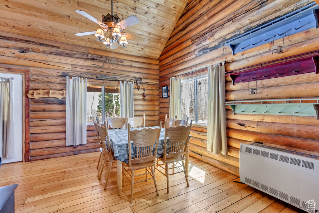 Dining space with radiator heating unit, wooden ceiling, high vaulted ceiling, light wood-type flooring, and log walls