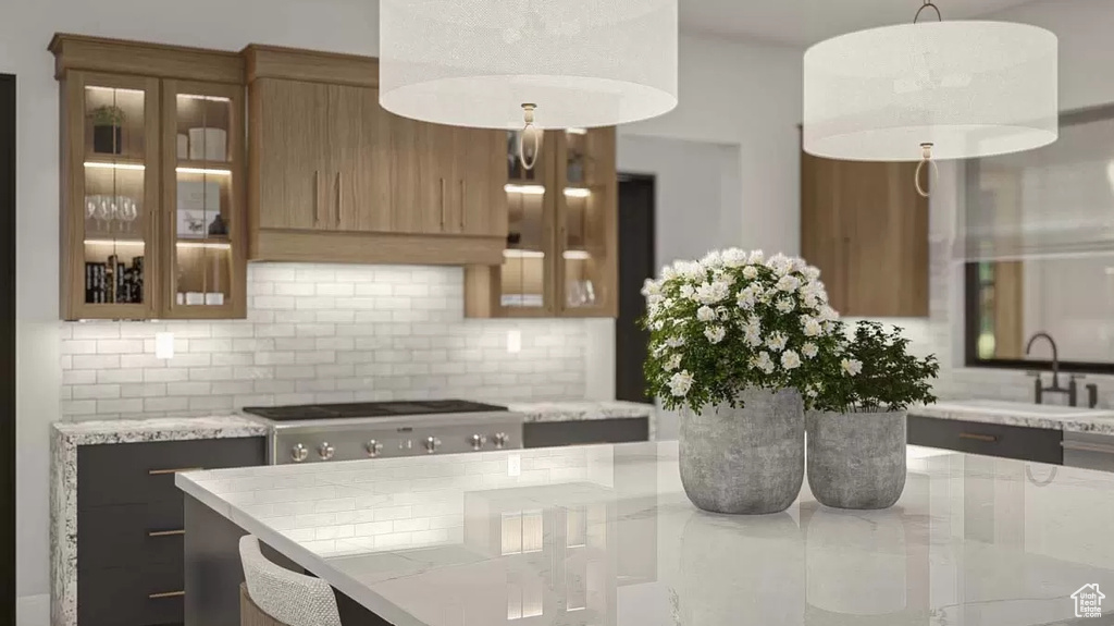 Kitchen with sink, light stone countertops, backsplash, and pendant lighting