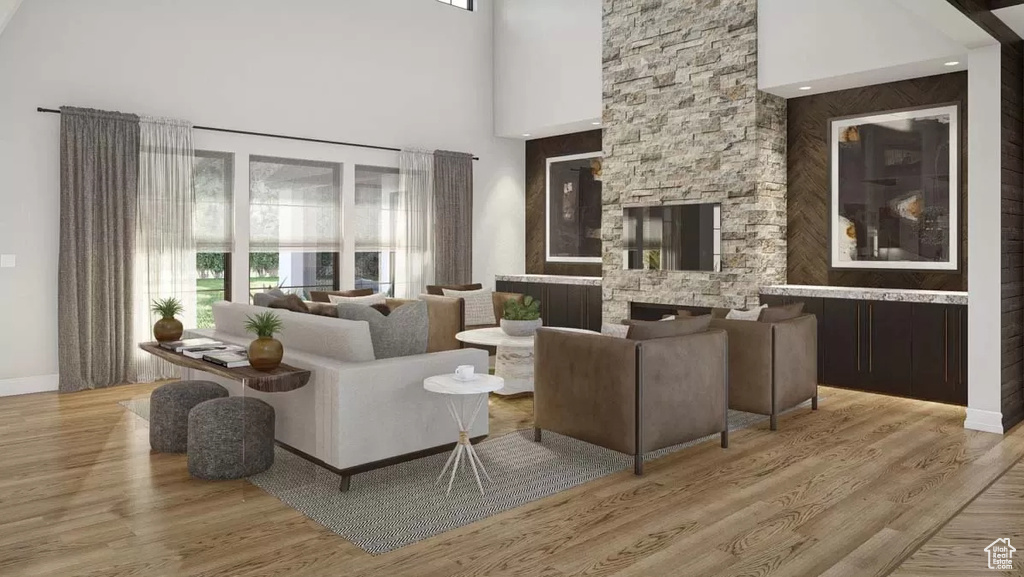 Living room featuring a stone fireplace, a high ceiling, and light hardwood / wood-style flooring