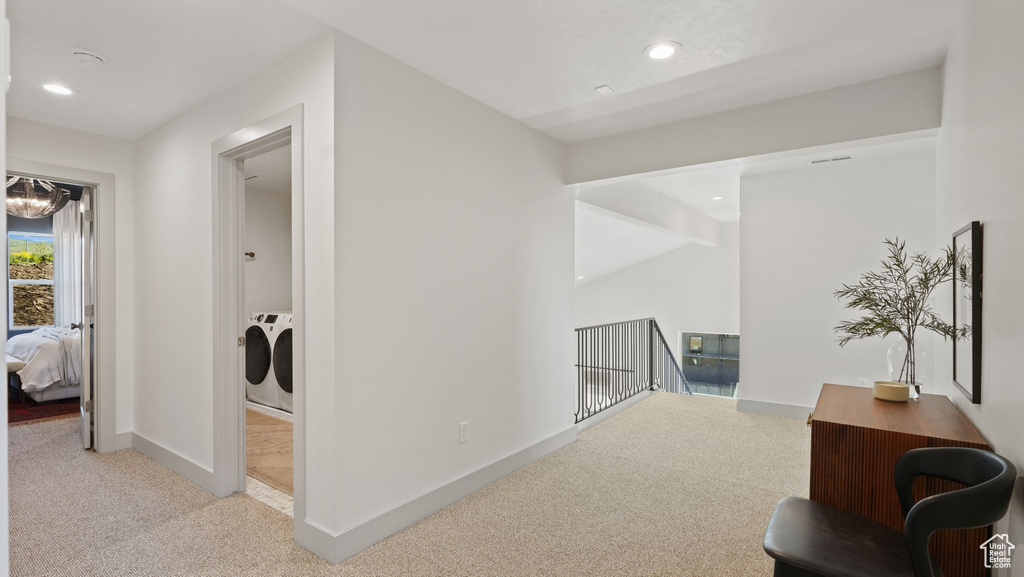 Corridor with light colored carpet, beamed ceiling, independent washer and dryer, and a notable chandelier