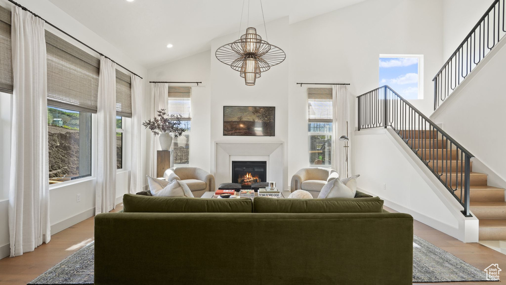 Living room featuring light hardwood / wood-style floors, high vaulted ceiling, and an inviting chandelier