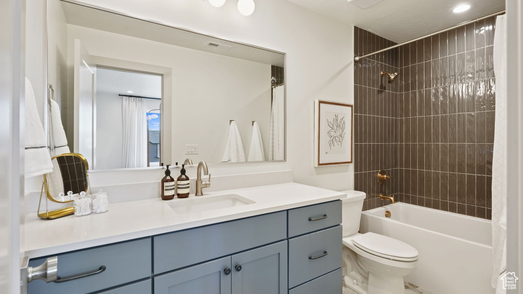 Full bathroom featuring tiled shower / bath, vanity, and toilet