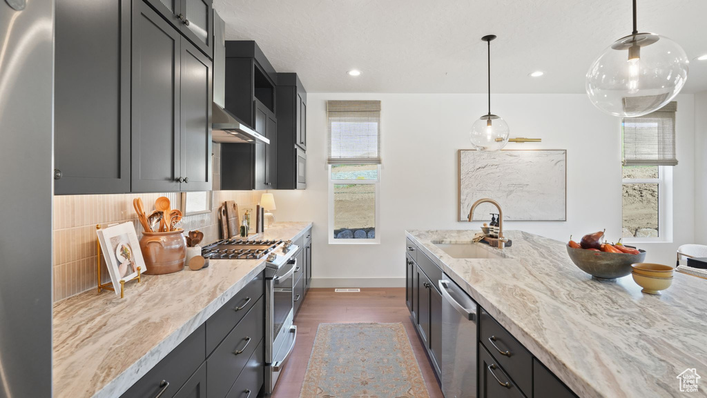 Kitchen with stainless steel appliances, a healthy amount of sunlight, backsplash, and sink