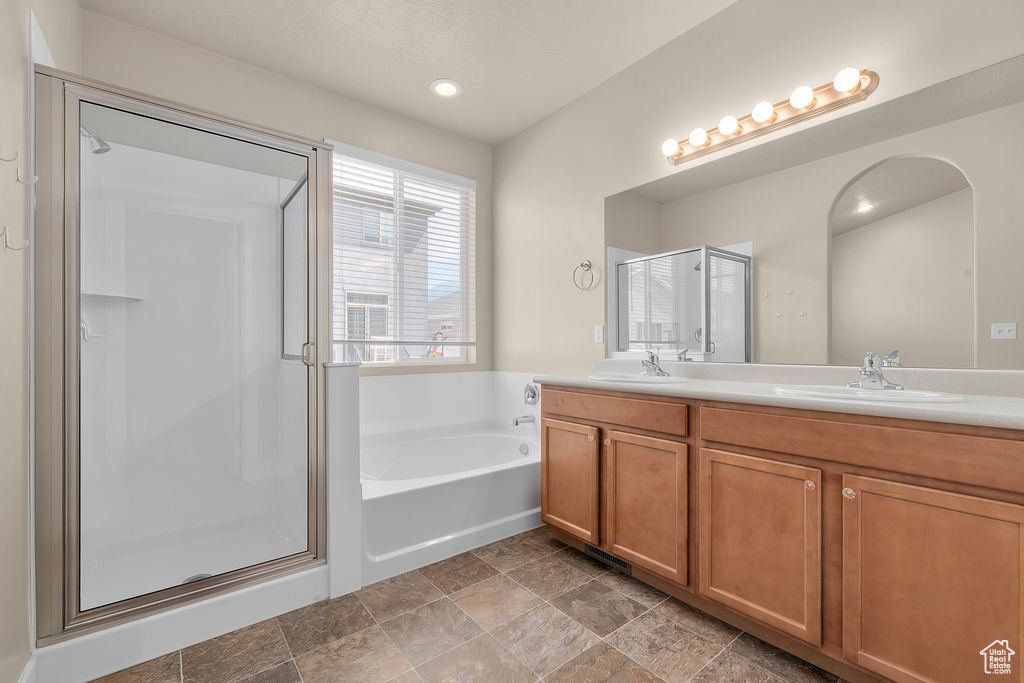 Bathroom with double vanity, tile flooring, and plus walk in shower