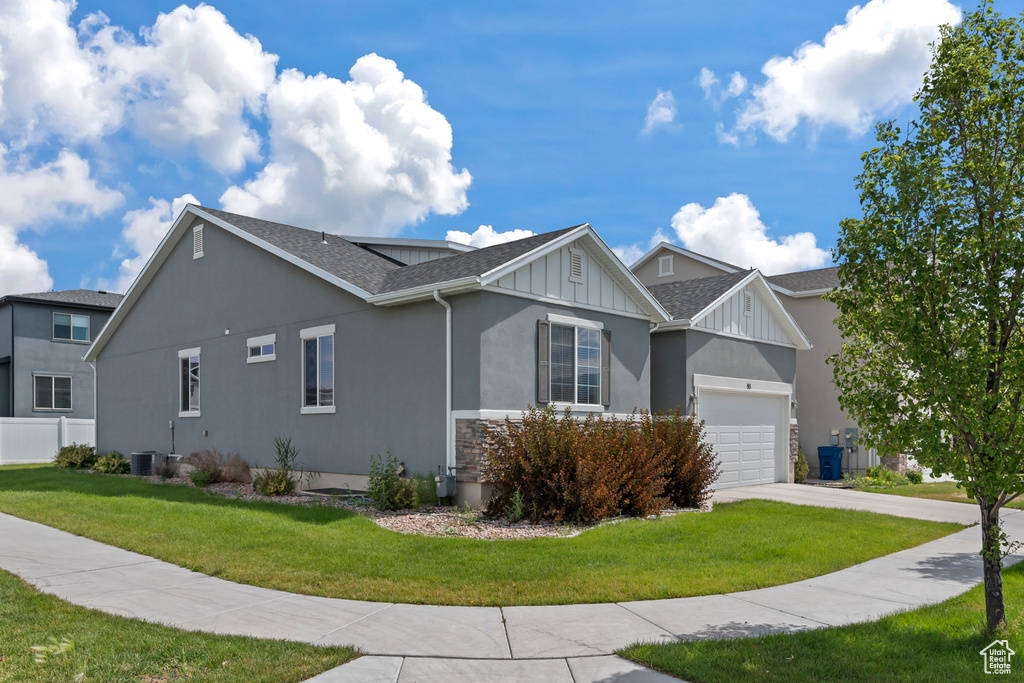 View of home\'s exterior featuring a garage, central AC, and a yard