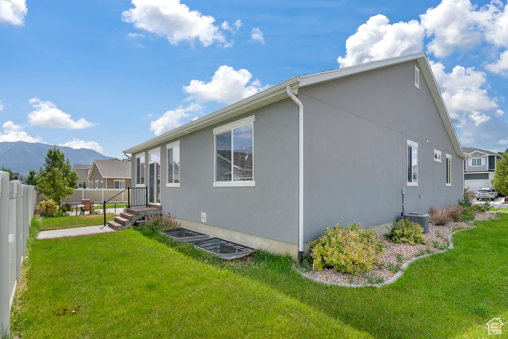 View of home\'s exterior featuring central AC unit, a lawn, and a mountain view