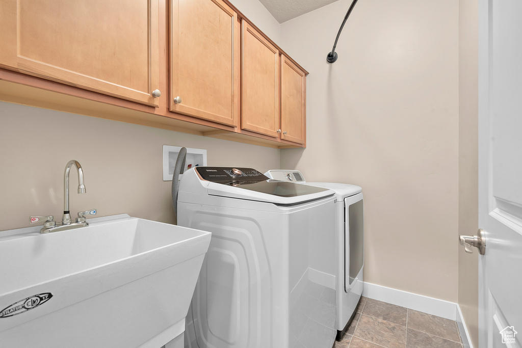 Washroom featuring hookup for a washing machine, washer and dryer, light tile floors, sink, and cabinets