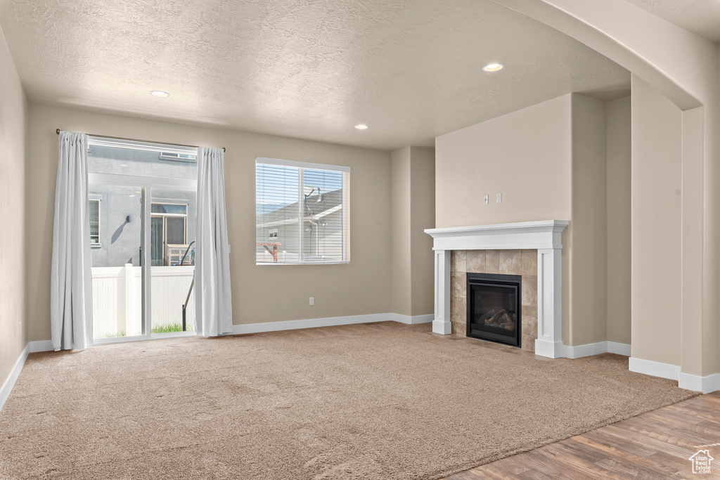 Unfurnished living room with a textured ceiling, a fireplace, and light colored carpet