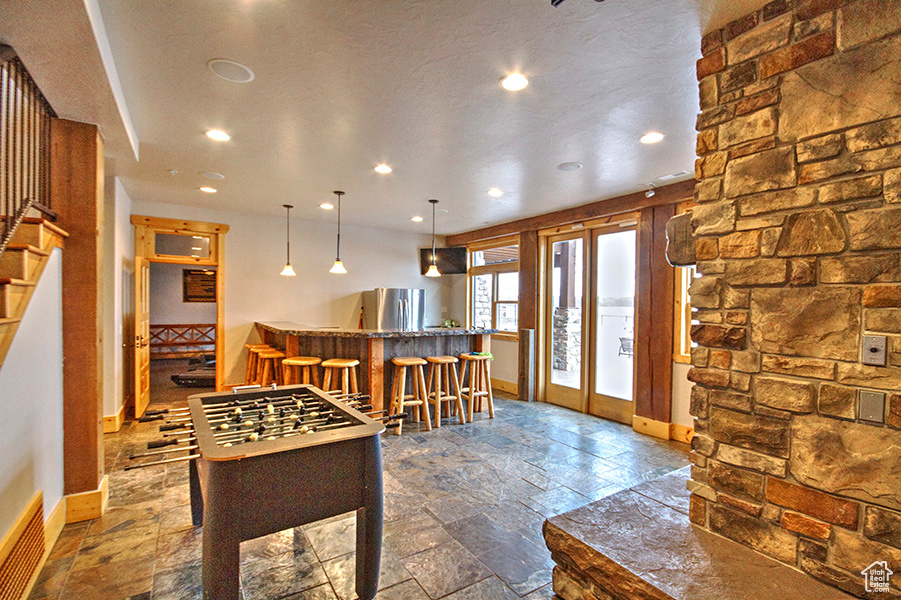 Recreation room featuring french doors, indoor bar, a textured ceiling, and tile floors