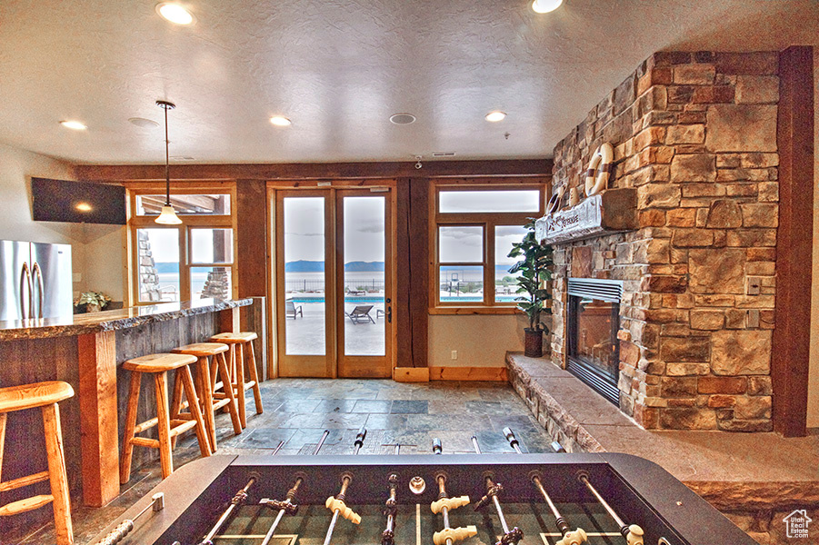 Unfurnished living room with a stone fireplace, tile flooring, plenty of natural light, and a textured ceiling