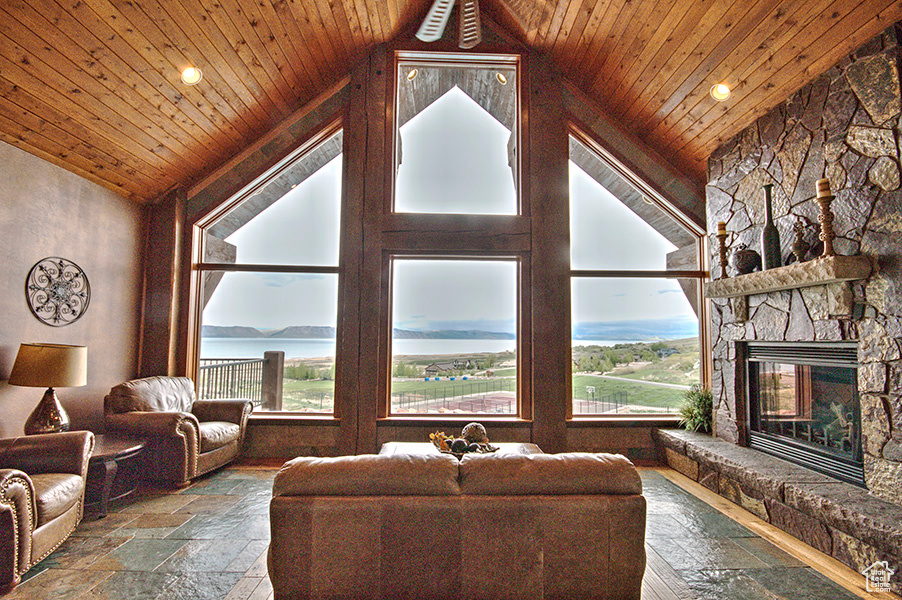 Tiled living room featuring high vaulted ceiling, a fireplace, and wood ceiling