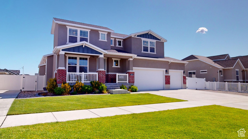 Craftsman inspired home with a porch, a garage, and a front lawn