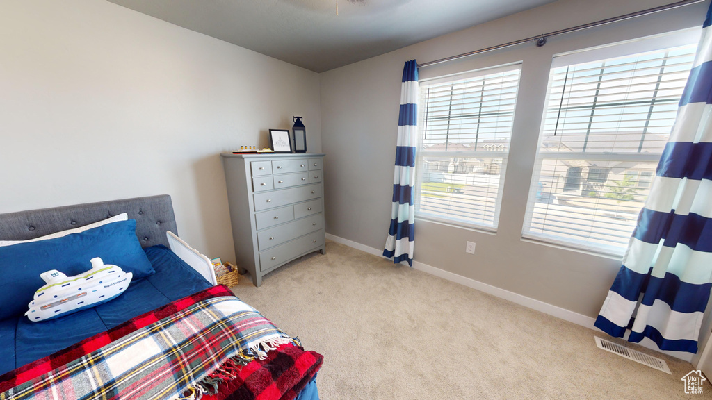 Carpeted bedroom featuring multiple windows