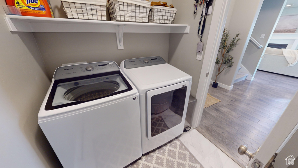 Laundry area with washer and dryer and light hardwood / wood-style flooring