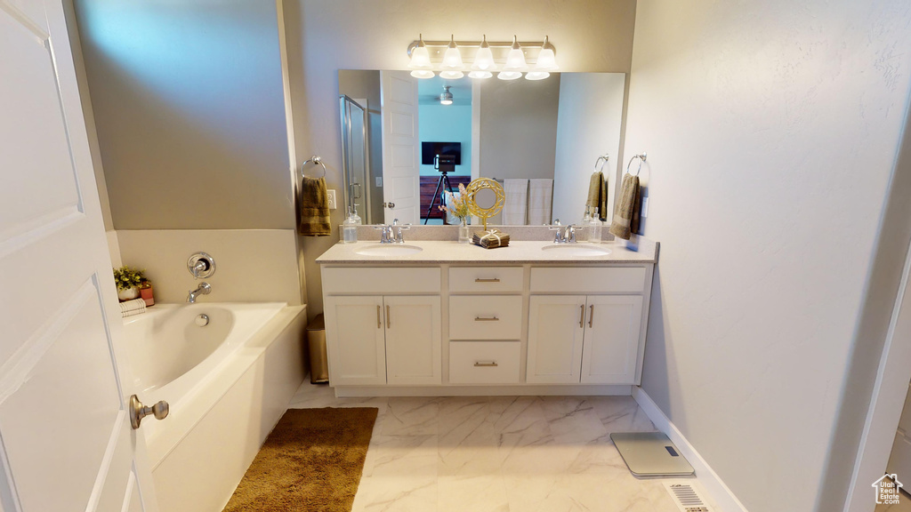 Bathroom with tile flooring, double sink vanity, and a bath to relax in