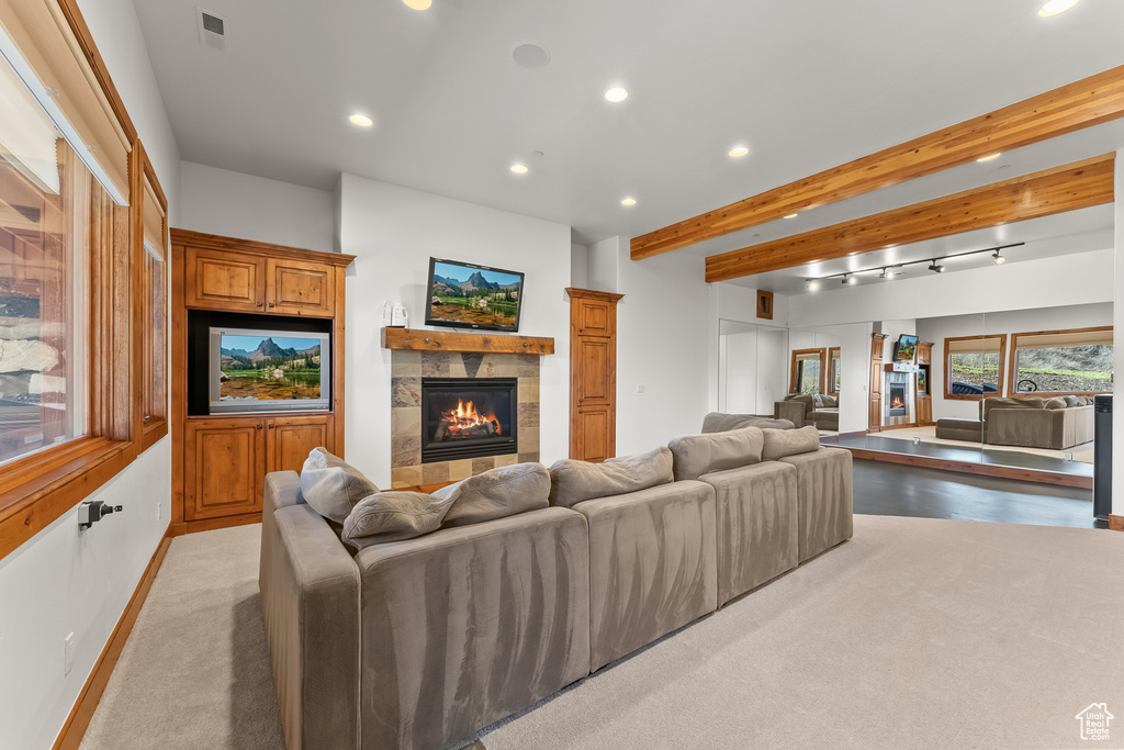 Carpeted living room with a tiled fireplace and beam ceiling