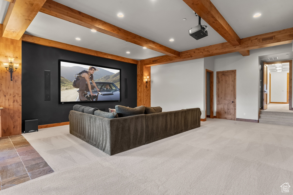 Home theater room with beamed ceiling and light carpet