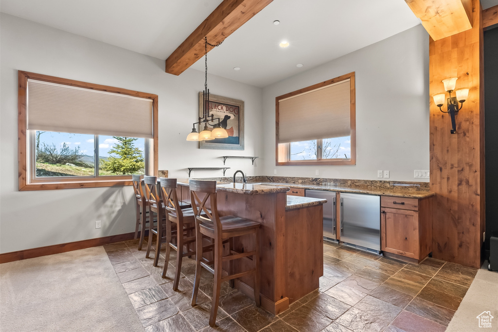 Bar with stone countertops, beam ceiling, decorative light fixtures, sink, and dark tile floors