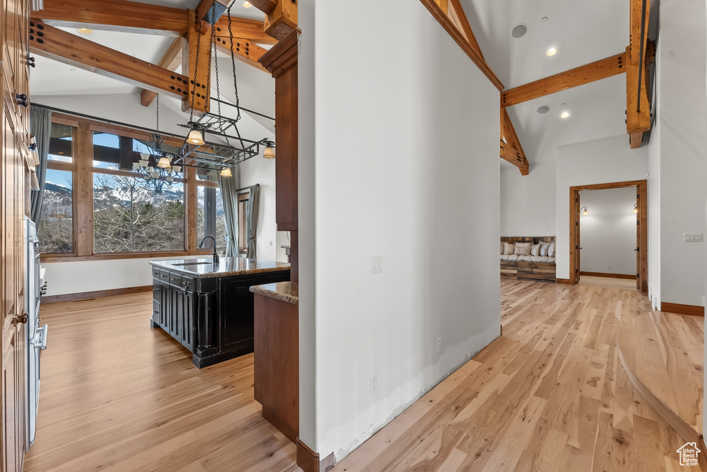 Corridor featuring high vaulted ceiling, beam ceiling, light hardwood / wood-style floors, and sink