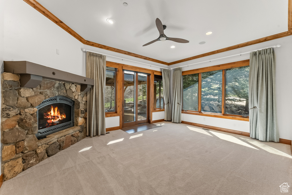 Unfurnished living room with carpet flooring, ornamental molding, ceiling fan, and a fireplace