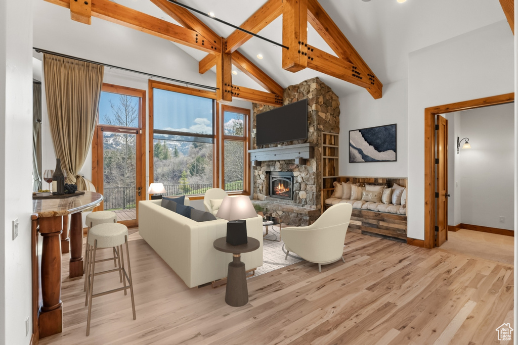 Living room with high vaulted ceiling, beam ceiling, light hardwood / wood-style floors, and a fireplace