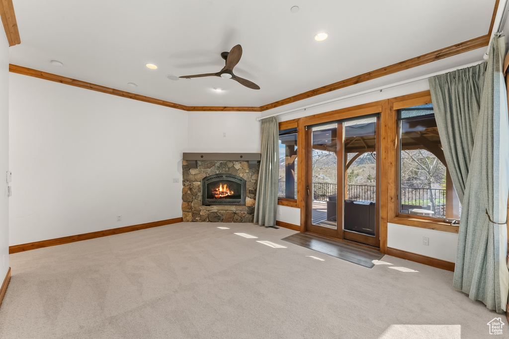 Unfurnished living room with a fireplace, ceiling fan, crown molding, and carpet flooring