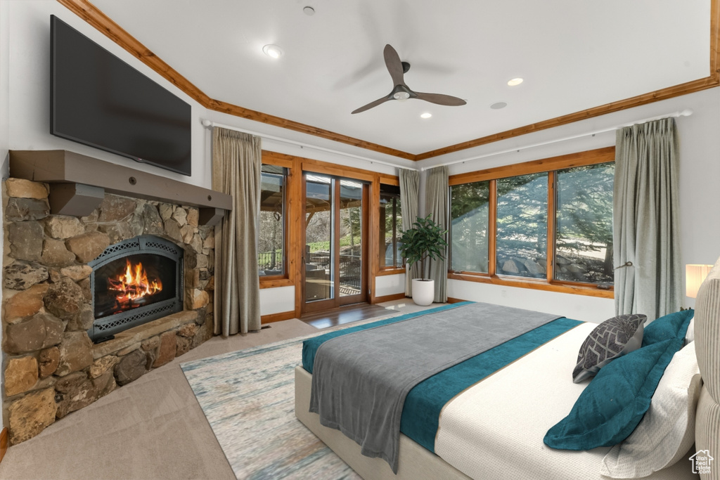 Bedroom with a stone fireplace, crown molding, ceiling fan, and access to exterior