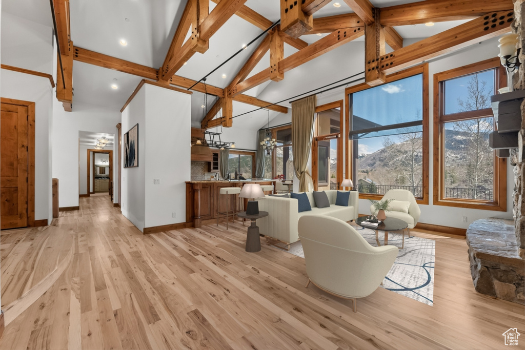 Living room with high vaulted ceiling, a mountain view, beam ceiling, and light wood-type flooring