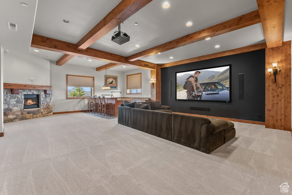 Home theater room with beam ceiling, a fireplace, and carpet