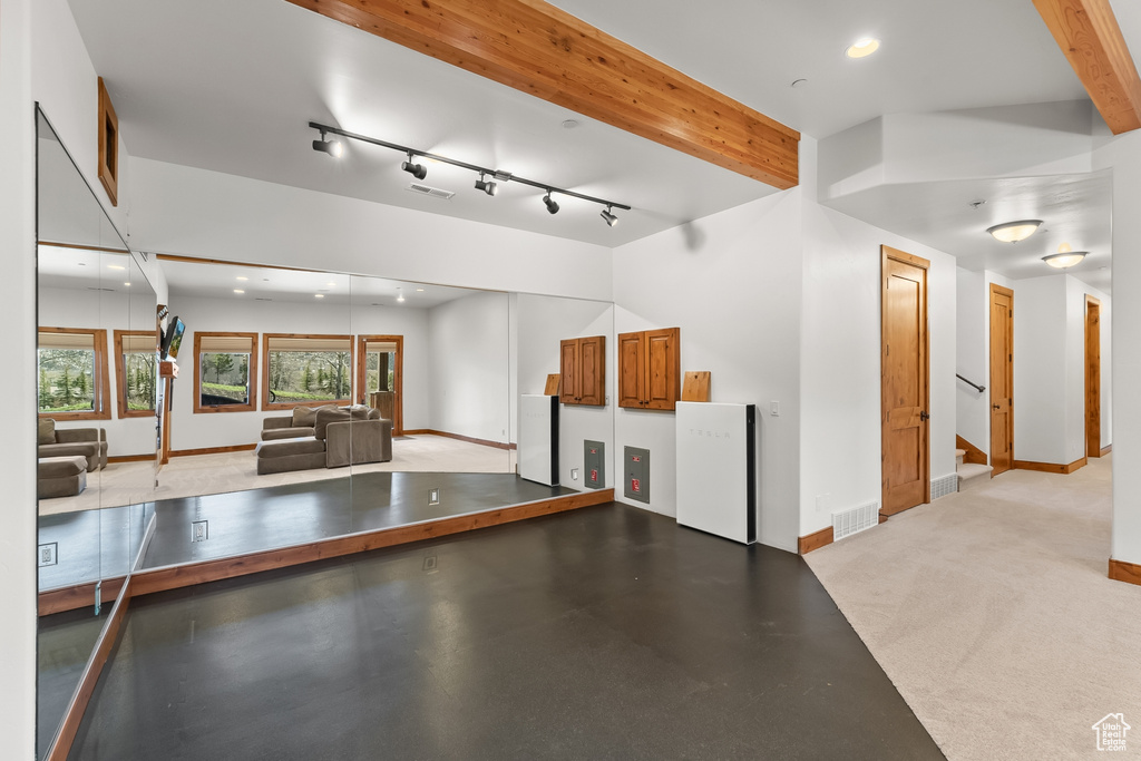 Interior space with beamed ceiling, light colored carpet, and track lighting