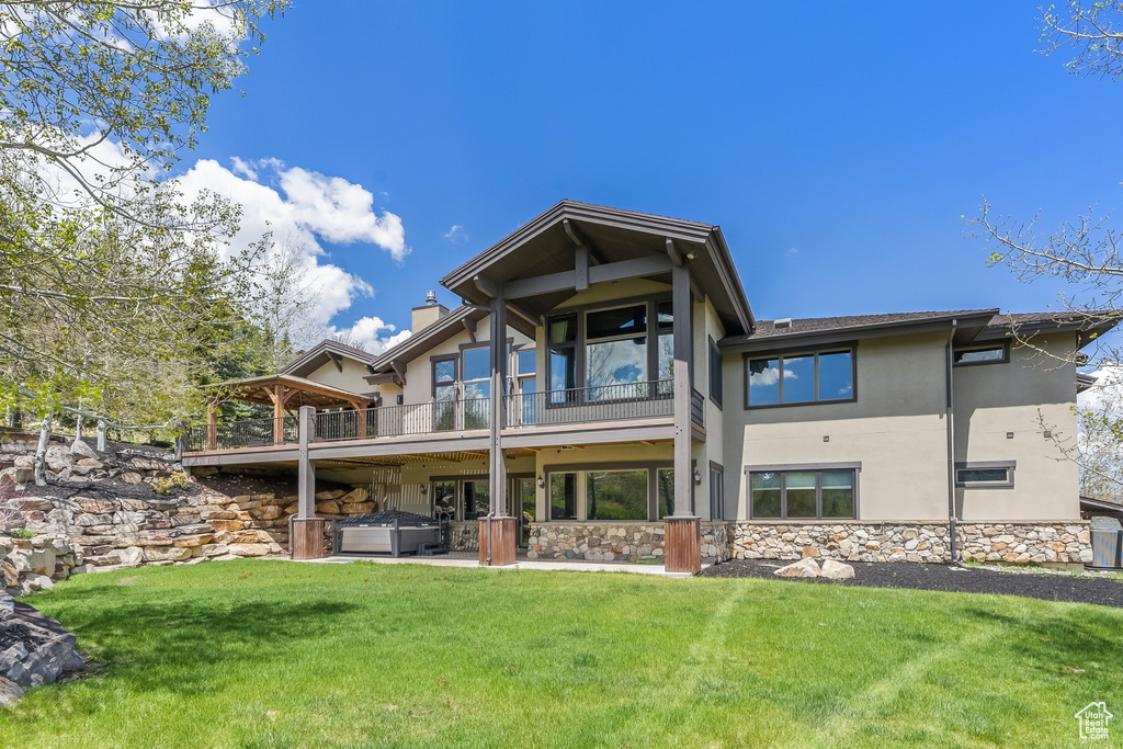 Rear view of property with a balcony and a yard