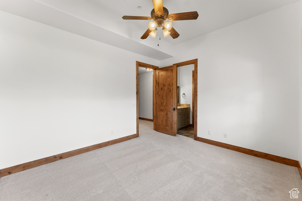 Unfurnished bedroom with light carpet, ceiling fan, and ensuite bath