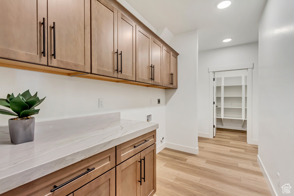 Kitchen with light stone counters and light hardwood / wood-style flooring