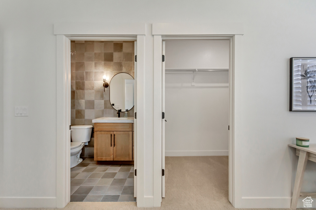 Bathroom with tile walls, vanity, and toilet