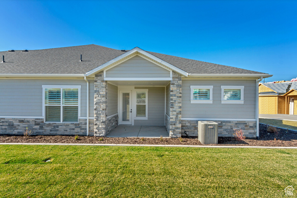 View of front of house featuring cooling unit, a front lawn, and a patio area