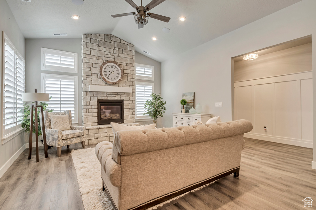 Living room with ceiling fan, light hardwood / wood-style flooring, a fireplace, and lofted ceiling