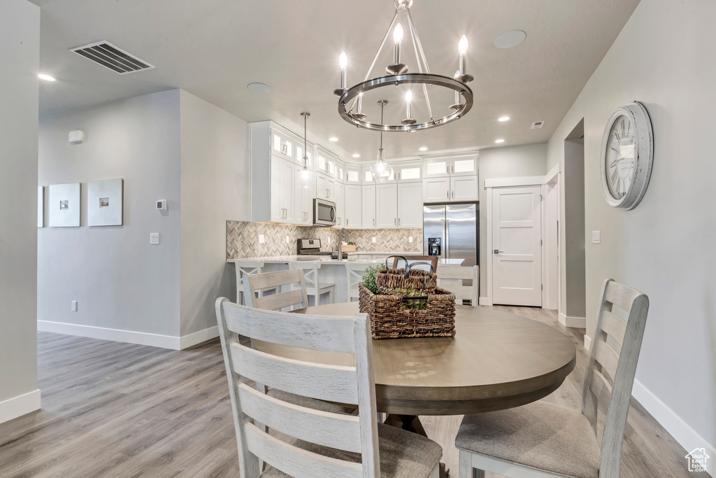 Dining space featuring light hardwood / wood-style floors and an inviting chandelier