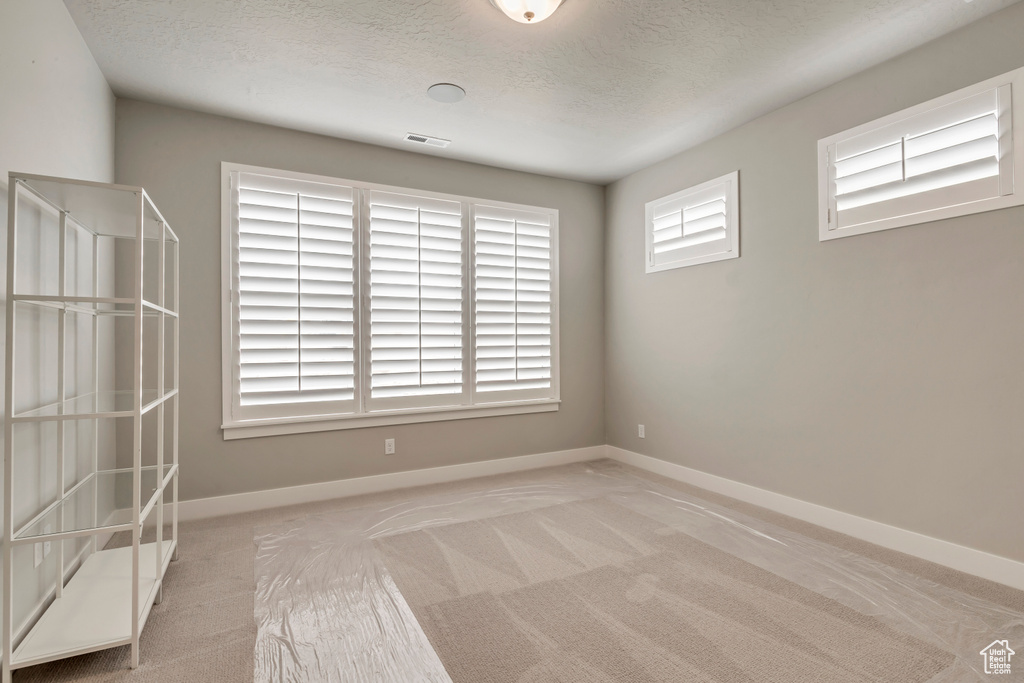 Carpeted spare room featuring a textured ceiling