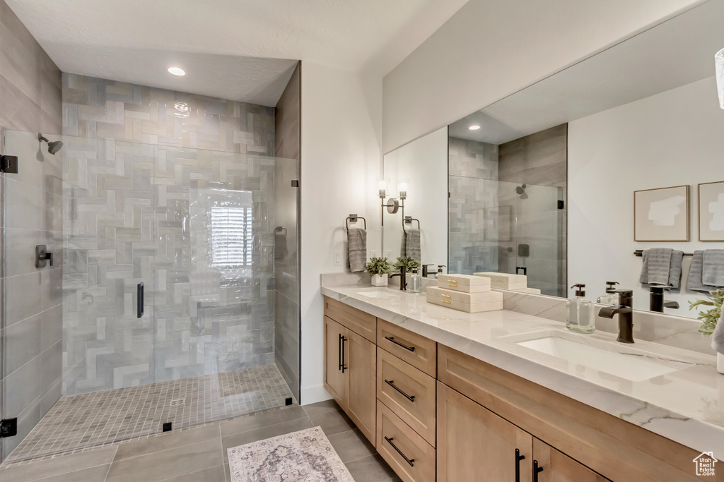 Bathroom featuring a shower with shower door, vanity, and tile patterned floors