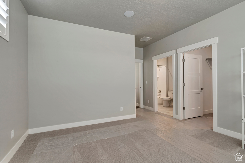 Empty room featuring a textured ceiling and carpet floors