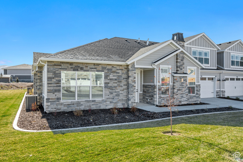 Back of house featuring a garage, central air condition unit, and a yard