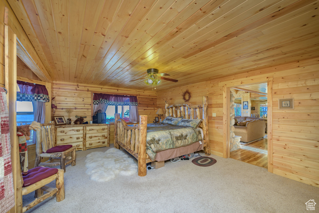 Bedroom featuring carpet flooring, wooden walls, and wood ceiling