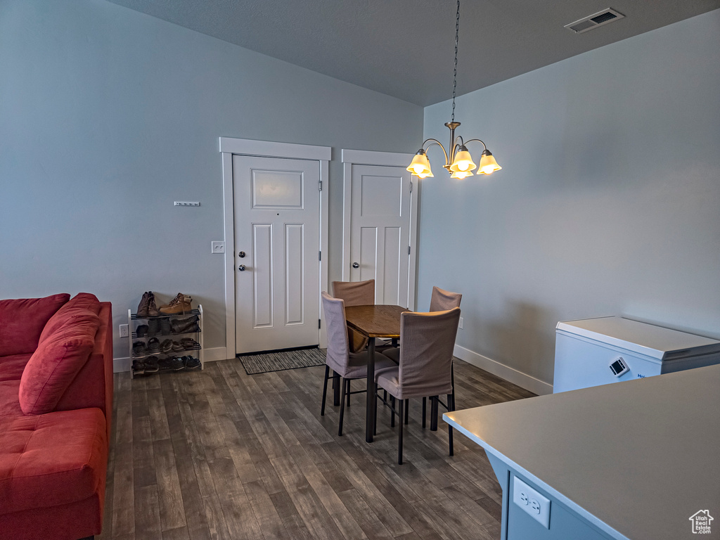 Dining room with a notable chandelier and dark wood-type flooring